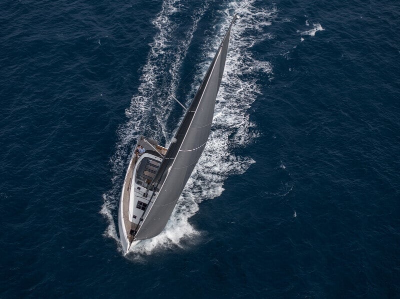 Ylhäältä kuvattu Jeanneau Yachts 55, jossa miehistö ja matkustajat nauttivat peräkannen mukavuuksista ja uimatasosta.